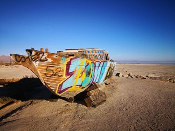 Colorful boat moored at beach against clear blue sky