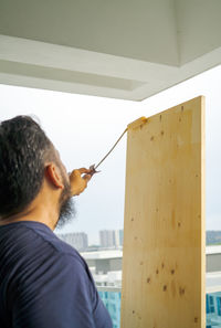 Applying clear coat paint on a wooden surface with roller brush. painting wood wall and floor.