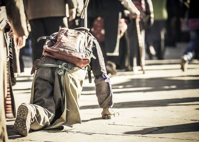 Rear view of disabled man crawling on footpath