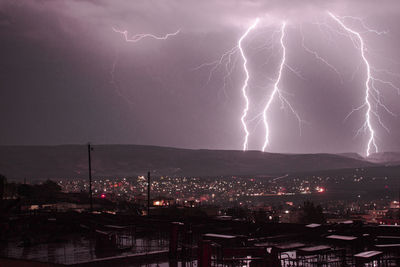 Lightning over illuminated buildings in city at night