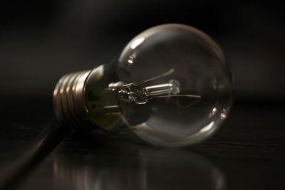 Close-up of light bulb on table in darkroom