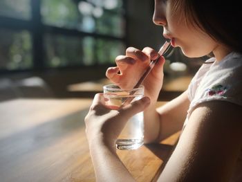 Midsection of woman drinking glass on table