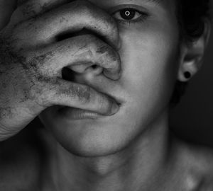 Close-up portrait of teenage boy with messy hand on face