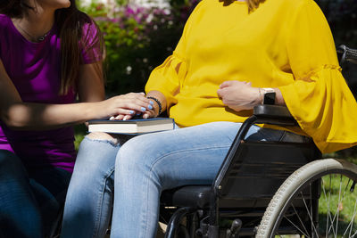 Daughter consoling mother sitting on wheelchair with book