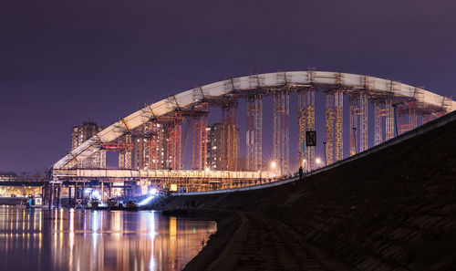 Illuminated bridge over river against sky at night