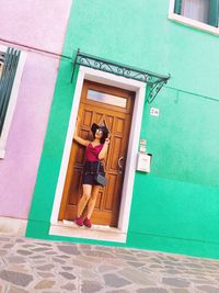 Woman standing against door of building