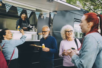 Customers standing for street food by commercial land vehicle in city