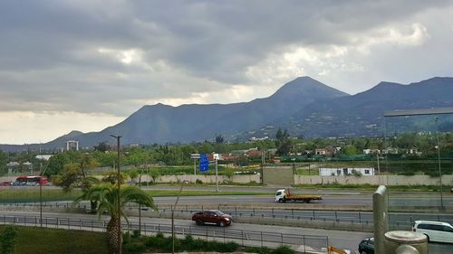 Cars on road by mountains against sky