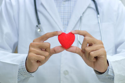 Midsection of doctor holding red heart shape