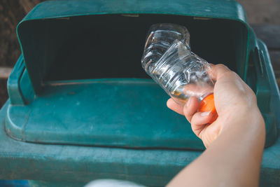 Close-up of hand putting bottle in dustbin