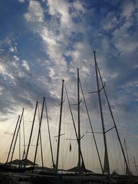 Low angle view of sailboats in sea against cloudy sky