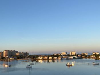 City buildings by sea against clear blue sky