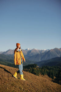 Rear view of woman standing on mountain against clear sky