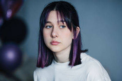 Portrait of a young girl with purple hair close-up on a gray background