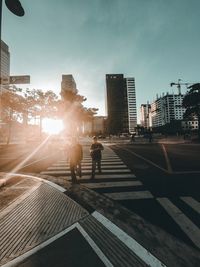 People walking on road against buildings in city