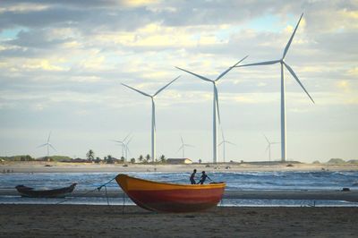 Traditional windmill on beach against sky