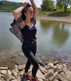 Full length of young woman standing on rock at beach