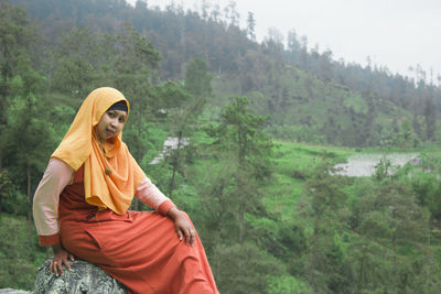 Close up photo of a woman outdoors with a green forest view