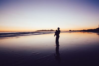 Full length of woman standing on beach during sunset