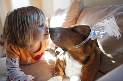 Girl lying by dog on sofa at home