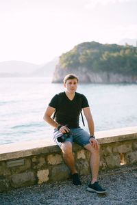 Portrait of man sitting on retaining wall