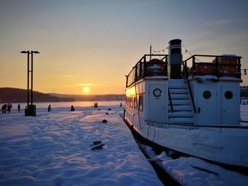 Boat moored at harbor against sky during sunset