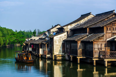 Houses by river against sky