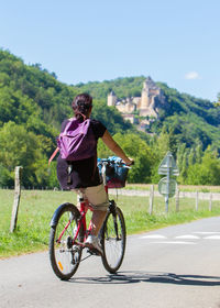 Rear view of man riding bicycle on road