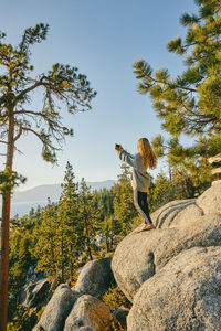 Young woman taking a picture of sunset over lake tahoe.