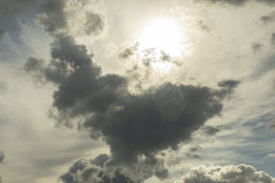 Low angle view of sunlight streaming through clouds