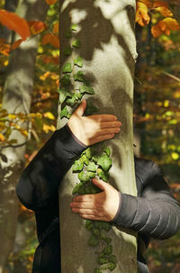 Midsection of man holding leaves while standing by plant