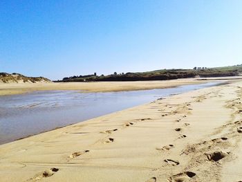 Scenic view of beach against clear blue sky