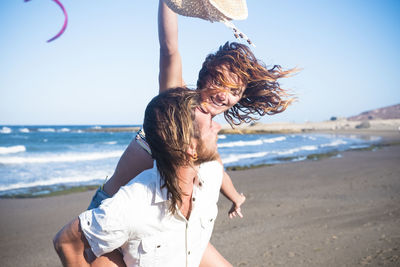 Midsection of woman at beach against sky