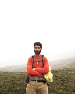 Portrait of man sitting on cliff against clear sky