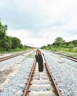 Rear view of woman standing on railroad track