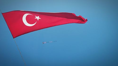 Low angle view of flag against clear blue sky