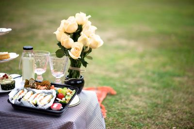 Rose vase with meal on table at grassy field