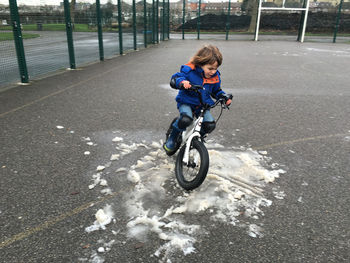 Boy skidding bicycle on snow at court