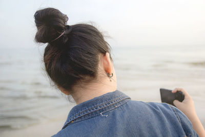 Rear view of woman on beach against sky