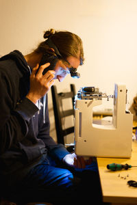 Side view of man reparing the sewing machine