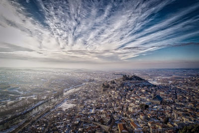 Aerial view of cityscape against cloudy sky