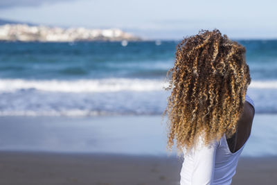 Woman with curly hair standing at beach