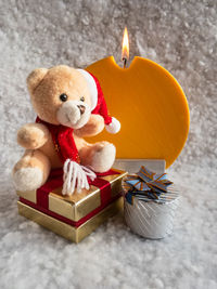 Close-up of stuffed toy with presents and candle on snow