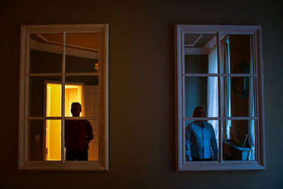 Woman and man standing by window at home building