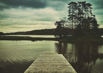 Pier on lake against cloudy sky