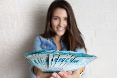 Portrait of a smiling young woman against wall