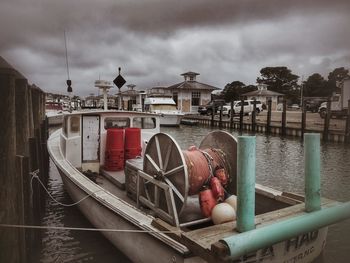 Boats moored at harbor against sky