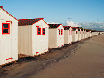 Houses on beach by buildings against sky