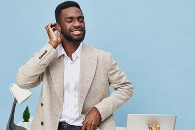 Portrait of young man standing against blue background