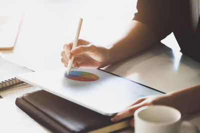 Midsection of woman using laptop at table